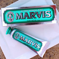Travel-size tube of Marvis toothpaste with packaging, displayed on a table with a white background.