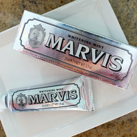 Two tubes of Marvis Whitening Mint toothpaste on a white surface.